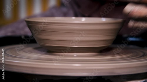Man makes a clay pot or vase on a potter's wheel