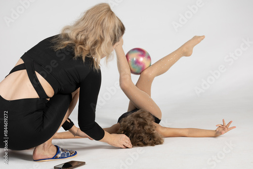 A female trainer teaches a girl gymnastics. The trainer shows her student how to perform gymnastics exercises correctly.