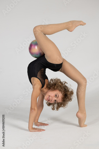 A girl gymnast demonstrates exercises with a ball.
