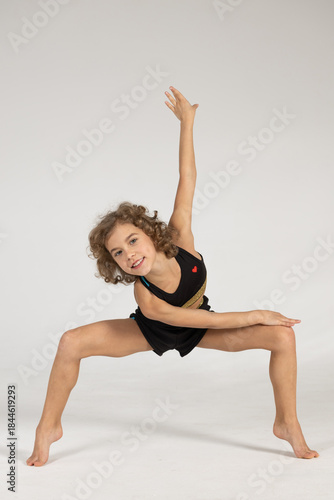 A girl in a tracksuit hones her skills. A woman practices rhythmic gymnastics.