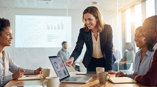 Businesswoman presenting analytical data on laptop to diverse team during a corporate meeting in modern office conference room