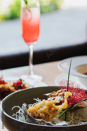 Gourmet dish served in a decorative bowl with a refreshing cocktail in a modern dining setting