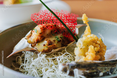 Gourmet seafood dish featuring crab, crispy garnish, delicate presentation, and garnished with herbs on a rustic plate