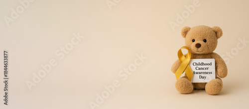Childhood cancer awareness day teddy bear with yellow ribbon and text space