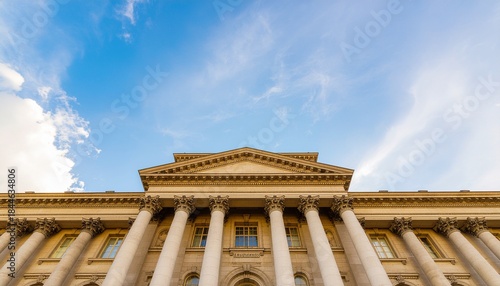 Historic building facade with neoclassical columns under a bright blue sky with clouds