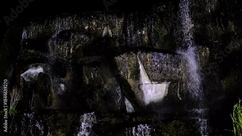 In a natural waterfall, water cascading down the rocks.