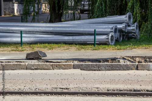 Road repairs. Metal lampposts lie on the side of the road.