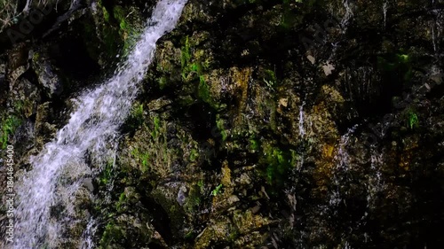In a natural waterfall, water cascading down the rocks.