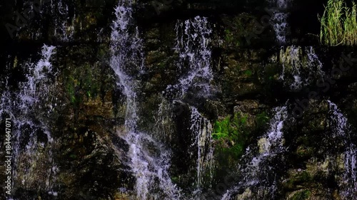 In a natural waterfall, water cascading down the rocks.