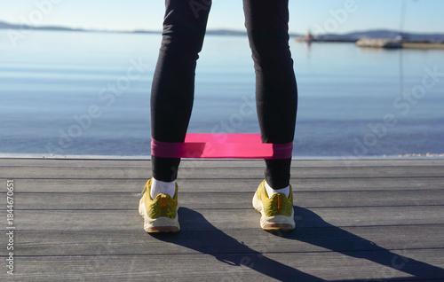 Outdoor resistance band workout showing woman preparing for exercise, fitness band, simple daily fitness routine, winter wellness, active lifestyle, strength training by the sea