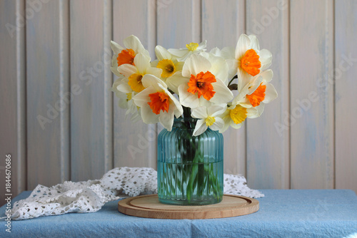 bouquet of garden daffodils of various varieties in blue glass vase on table