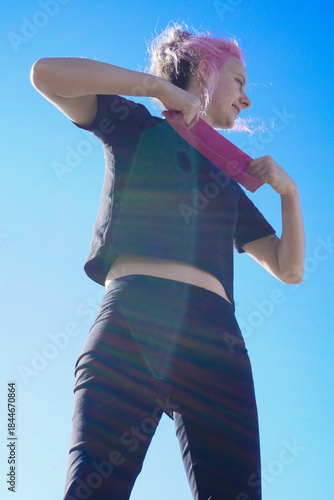 Morning outdoor fitness routine, woman training with resistance band in fresh air, simple daily exercise, active lifestyle, balance, wellness, self-care, and healthy habits.