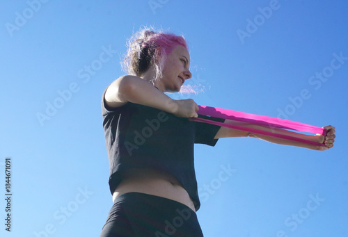 Morning outdoor fitness routine, woman training with resistance band in fresh air, simple daily exercise, active lifestyle, balance, wellness, self-care, and healthy habits.