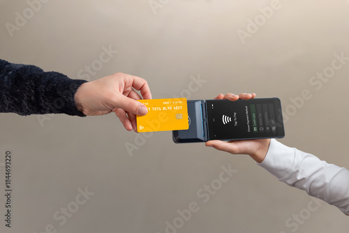 Contactless credit card tap to pay on mobile POS terminal held by cashier, showing modern wireless payment and digital checkout process