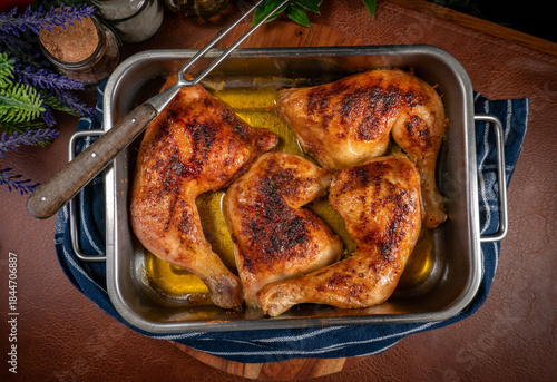 Baked chicken legs in metal baking dish.