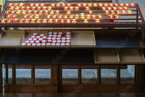 Votive stand in a church, which holds lit and unlit votive candles.