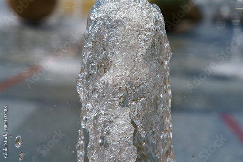 Water fountain sprays droplets into the air on a sunny day