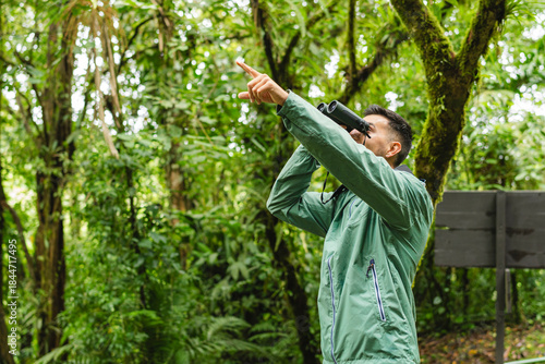 Young male birdwatcher pointing and using binoculars in Monteverde Cloud Forest Costa Rica