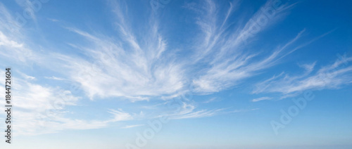 Beautiful blue sky with wispy clouds formations stretched across horizon. Natural cloud patterns create serene atmosphere, enhancing outdoor activities and relaxation.