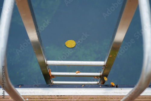 Metal handrail for descent into the lake, pier on the lake and calm lake water on background, selective focus