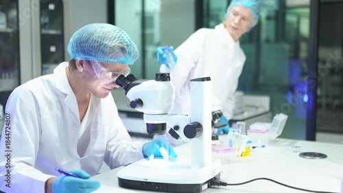 Scientists conduct research in laboratory using microscope and analyzing samples