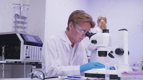 Young scientist examines samples under microscope in laboratory setting