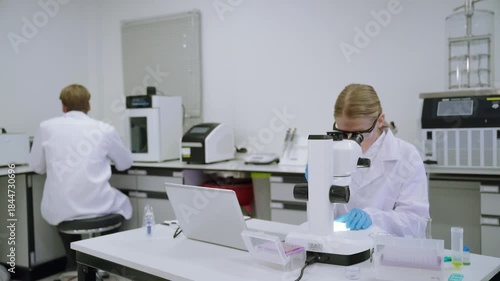 Research in a laboratory with scientists using a microscope and other equipment