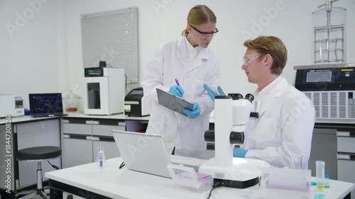 Scientists work in laboratory on research project with microscope and computer