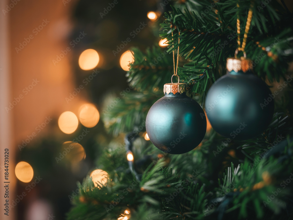 Fototapeta premium Close up of dark green christmas ornaments on a decorated evergreen tree with bokeh lights