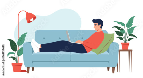 Young man relaxing on a comfortable sofa in his living room while working or browsing on his laptop computer at home.
