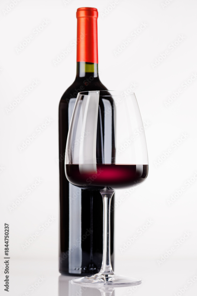 Obraz premium Red wine bottle and glass on white background