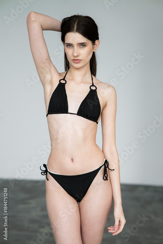 Young female fashion model in clean studio environment showing digitals and modelbook snaps for agency profile portfolio in bikini, frontal and profile angles	
