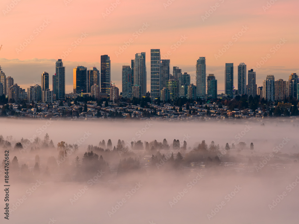Fototapeta premium Sunrise Over Foggy Burnaby Skyline as City Towers Rise Over Quiet Valley Below Morning Light