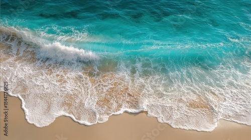 Waves crash onto the sandy beach under bright sunlight. The blue water creates white foam as it rolls in. Bright colors show clear sky and calm sea on a clear day.
