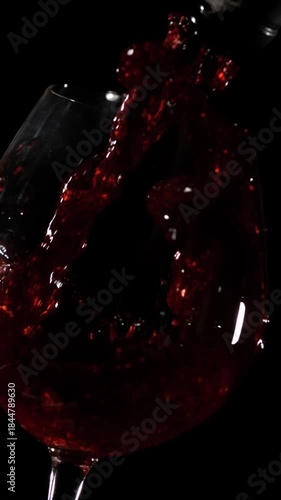 Enjoying red wine poured into a glass in a dark setting at a social gathering with friends and laughter