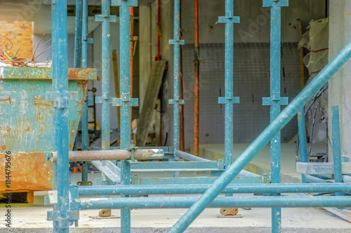 Construction site with blue scaffolding and a rusty dumpster