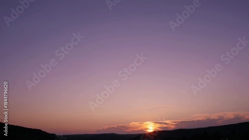 A serene sunset casting vibrant purple and orange hues over rolling hills. the expansive sky gradually darkens, creating a peaceful and calming atmosphere perfect for themes of relaxation and nature's