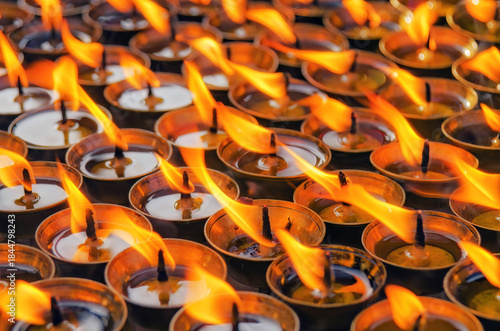 Rows of oil lamps in brass cups, flickering in unison
