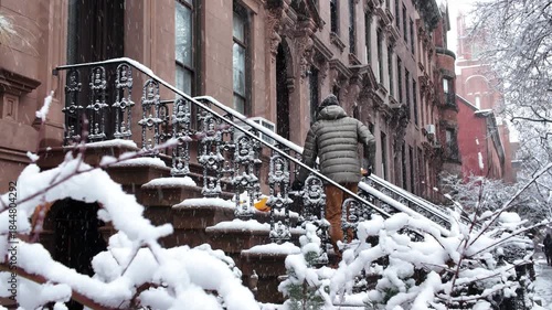 tighter shot of man shoveling snow on stoop in front of Brooklyn brownstones