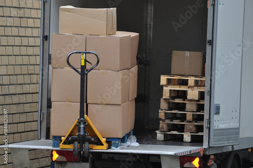 Pallet jack in the back of a big van unloading pallets with boxes of products