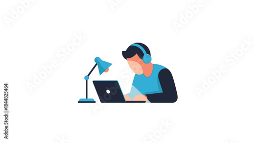Young man wearing headphones working on a laptop with a desk lamp.
