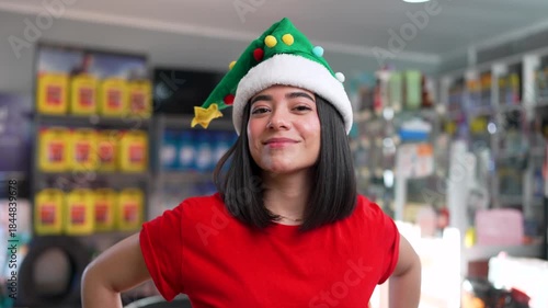 Young hispanic woman wearing a christmas elf hat and smiling in a car parts store