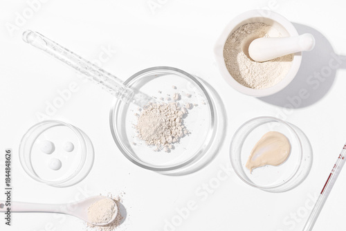 Petri dish with powder and laboratory equipment on white background