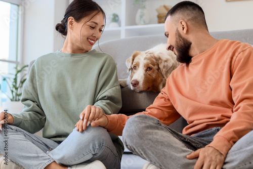 Young couple with Australian Shepherd dog sitting at home
