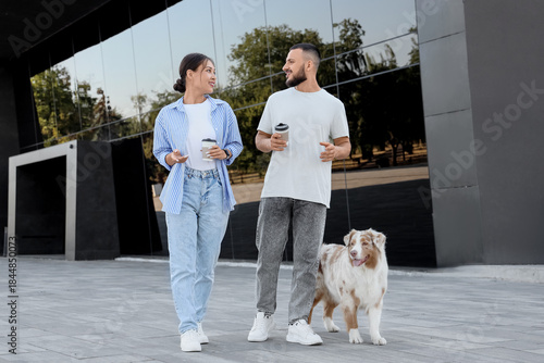 Young couple with coffee cups and Australian Shepherd dog outdoors