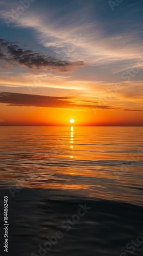 Vibrant Sunset Over Calm Ocean Reflecting Golden Sunlight and Fiery Orange Hues Amidst Wispy Clouds and Blue Sky