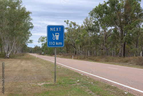 Roadside sign warning the next petrol gas fuel station is 110km away in a rural Australian area with eucalyptus trees