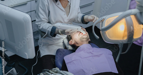 A female dentist performs dental treatment on a young patient using an intraoral scanner at a clinic.