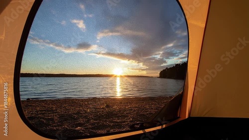 Sunset View Through Tent Opening Above Rocky Beach with Calm Water and Forest Horizon