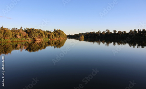 Reflection of trees on the calm glass-like surface of the Burdekin River near Charters Towers in Queensland, Australia
